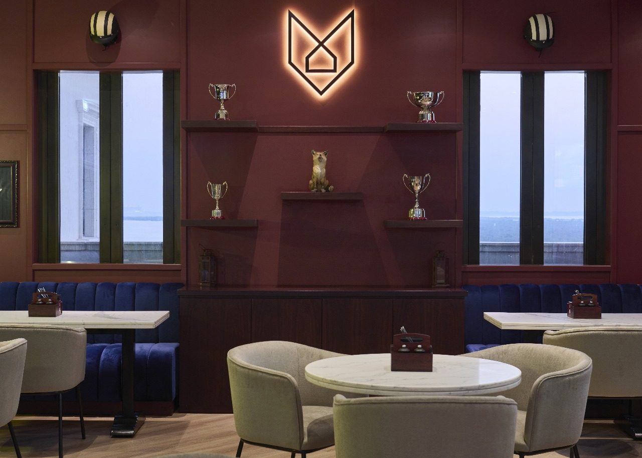 Crafty Fox restaurant feature wall in deep red joinery with a lit fox logo, floating shelves and velvet banquettes