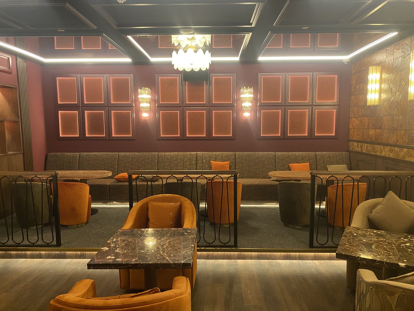 D’Lirio lounge fit-out: framed panelled walls, a long banquette, marble tables and velvet armchairs